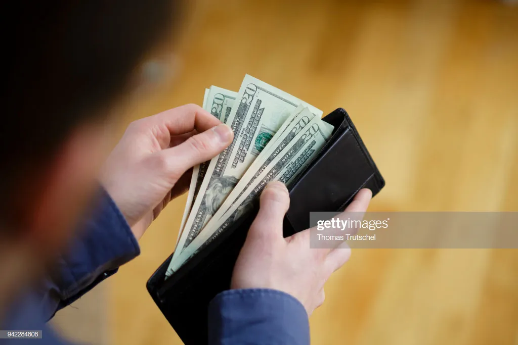 A person holds a wallet filled with U.S. dollar bills in a file photo. (Thomas Trutschel/Photothek via Getty Images)