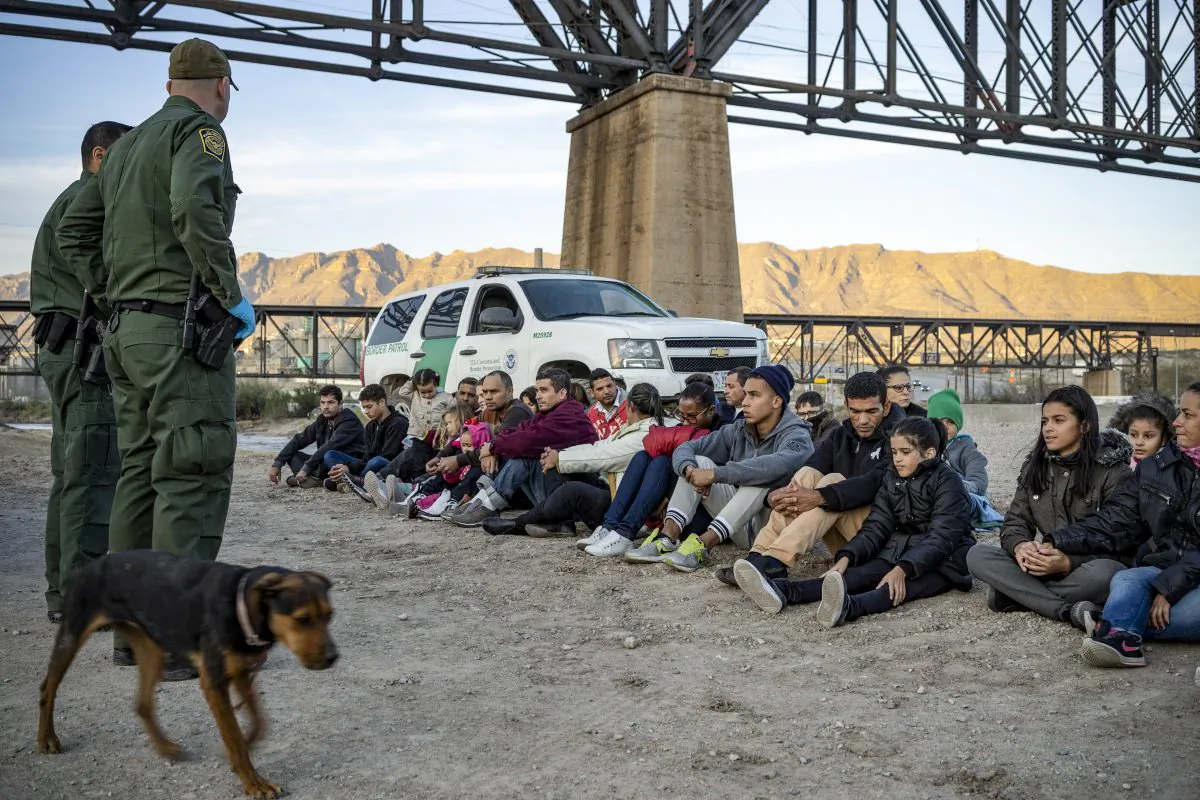 A group of about 30 Brazilian illegal immigrants, who had just crossed the border, sit on the ground near Border Patrol agents, on the property of Jeff Allen, on the U.S.–Mexico border in Sunland Park, New Mexico, on March 20, 2019. (Paul Ratje/AFP/Getty Images)