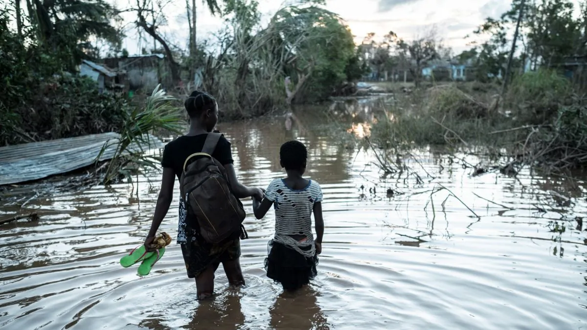 Two children walk in flooded waters from their house destroyed by the cyclone Idai, to go to seep in a shelter in Buzi, Mozambique, on March 22, 2019. (Yasuyoshi Chiba / AFP)
