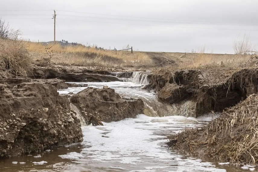 Following spring flooding water gushes along the driveway to Betty Lou Brave Heart's home near Porcupine, S.D., on the Pine Ridge Indian Reservation on March 25, 2019. (Ryan Hermens/Rapid City Journal via AP)