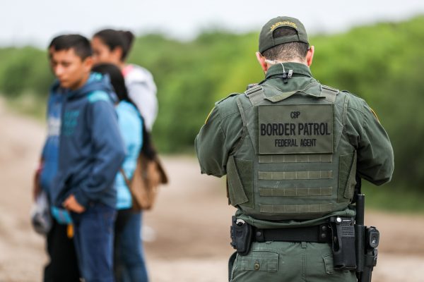 A Border Patrol agent apprehends illegal aliens who have just crossed the Rio Grande from Mexico into Penitas, Texas