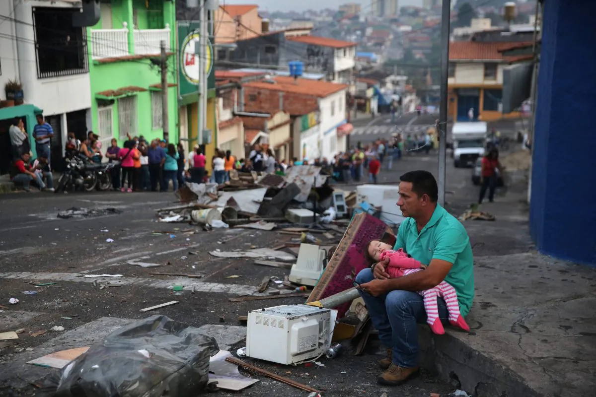 A father and daughter rest while someone holds their place before sunrise in a long line to buy basic foodstuffs at a supermarket on March 8, 2014 in San Cristobal, the capital of Tachira state, Venezuela.  John Moore/Getty Images