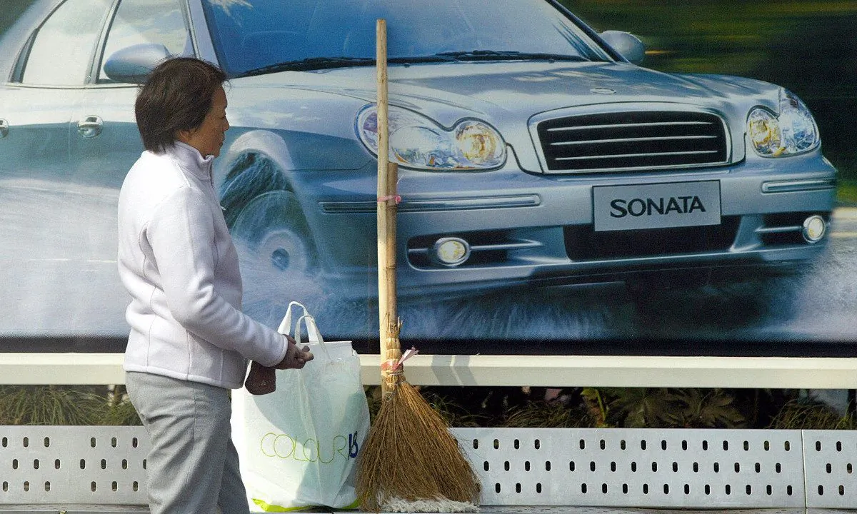 A woman stands in front of a car advertisement. (Liu Jin/AFP/Getty Images)