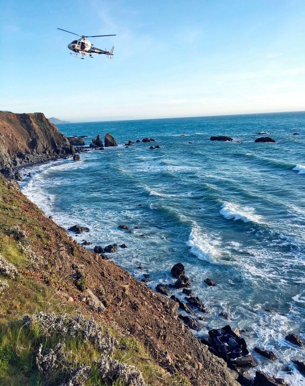 A helicopter hovers over steep coastal cliffs near Mendocino