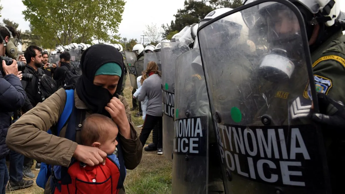 A woman holds her baby in front of riot police as migrants and refugees, who say that they seek to travel onward to northern Europe, walk away from a camp near the town of Diavata in northern Greece, on April 5, 2019. (Alexandros Avramidis/Reuters)