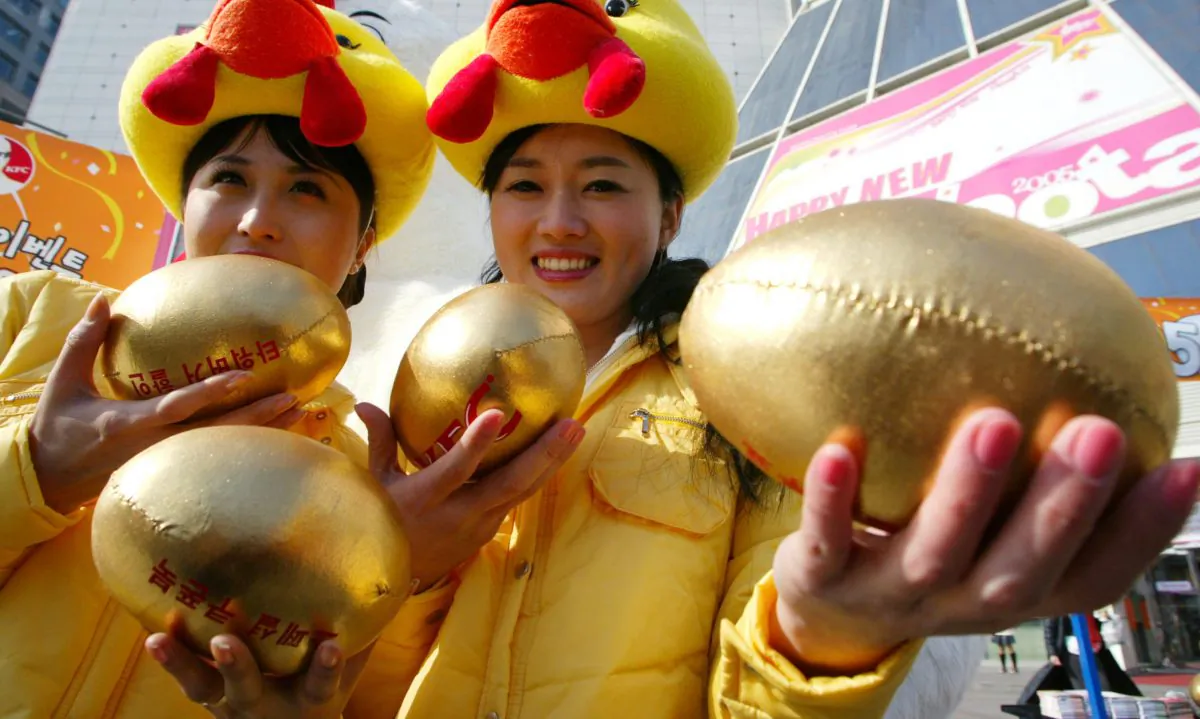 Women holding stuffed golden eggs. (Chung Sung-Jun/Getty Images)