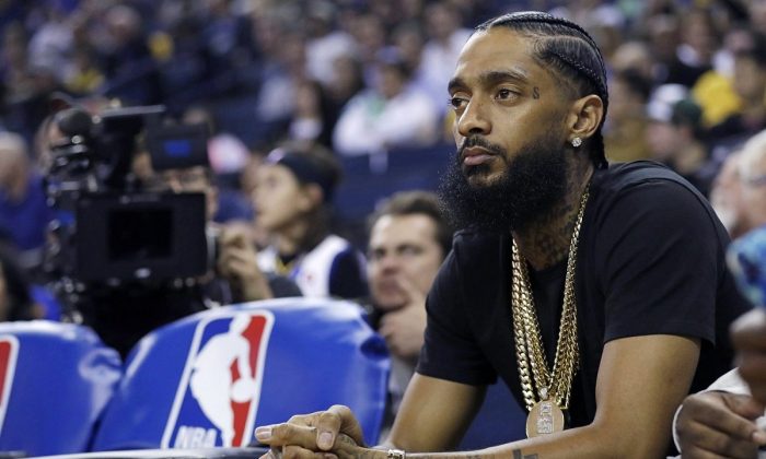 The rapper Nipsey Hussle watches an NBA basketball game between the Golden State Warriors and the Milwaukee Bucks in Oakland, Calif., on March 29, 2018. (Marcio Jose Sanchez/AP Photo)