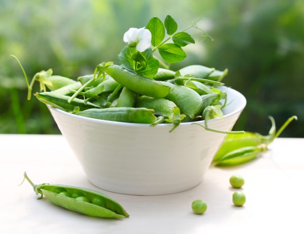 fresh peas in bowl with flower