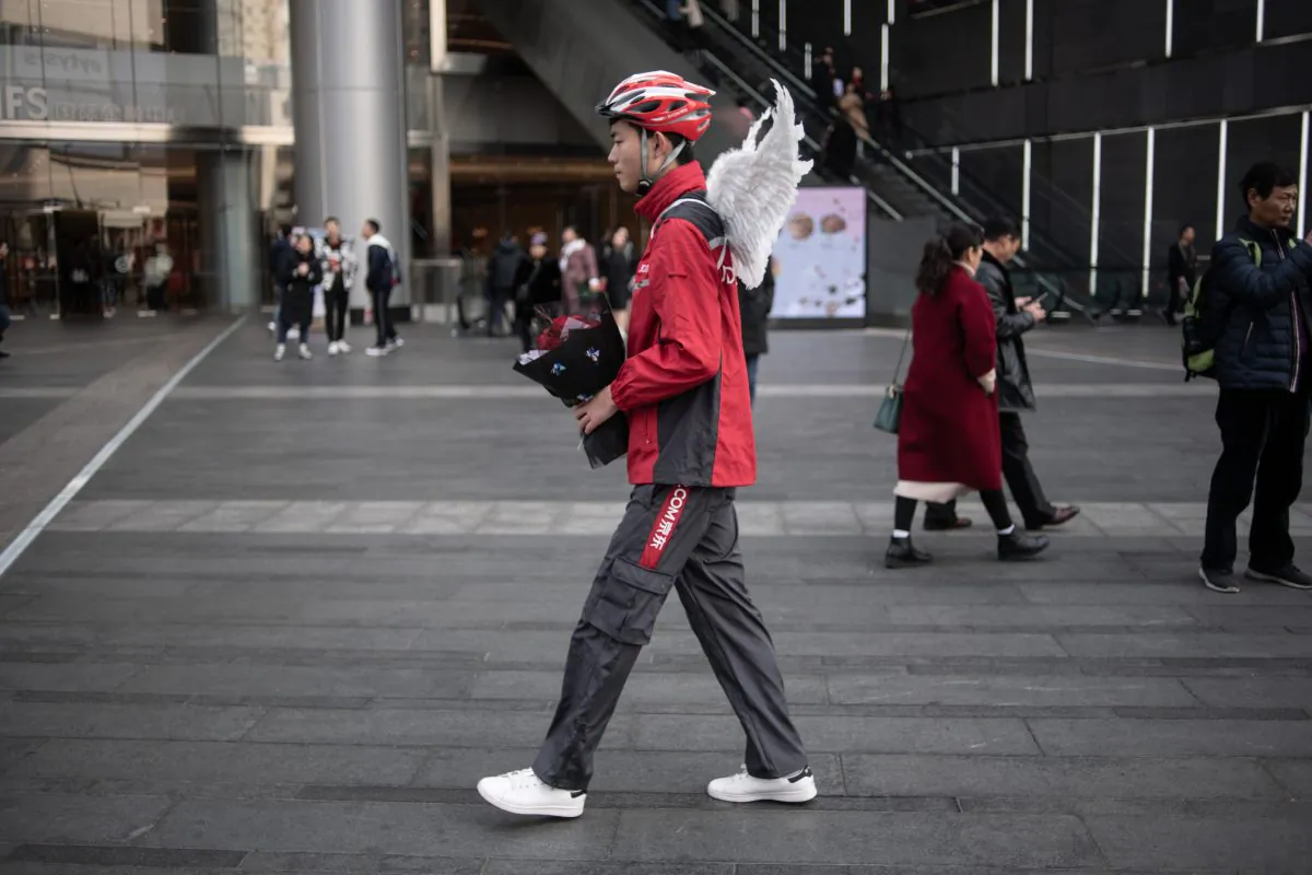 A delivery worker holding a bouquet of flowers and wearing wings poses during a Valentine's day event by Chinese e-commerce company JD.com in Chengdu, China's Sichuan province on February 12, 2019. (FRED DUFOUR/AFP/Getty Images)