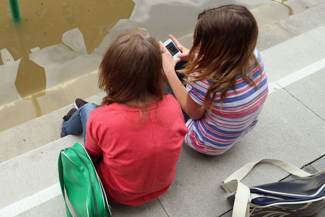 Two girls sit and discuss apps on their phones. (Sean Gallup/Getty Images)