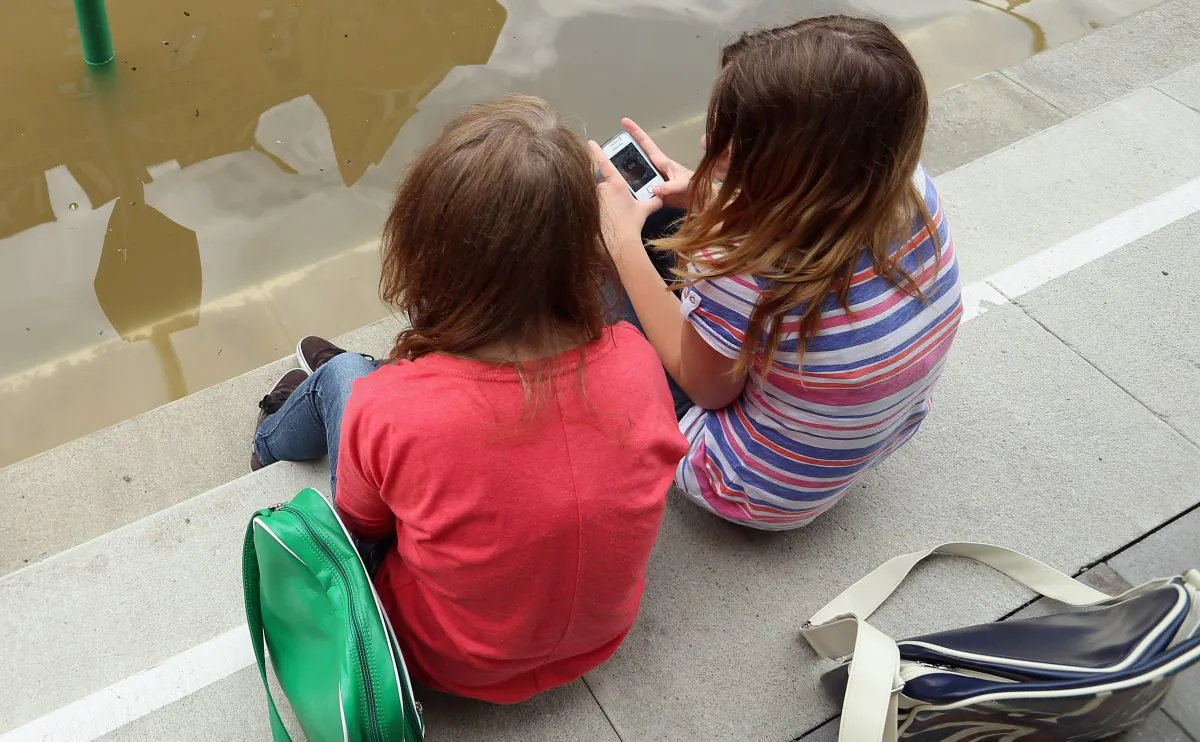 Undated image of two girls sitting and discussing apps on their phones. (Sean Gallup/Getty Images)