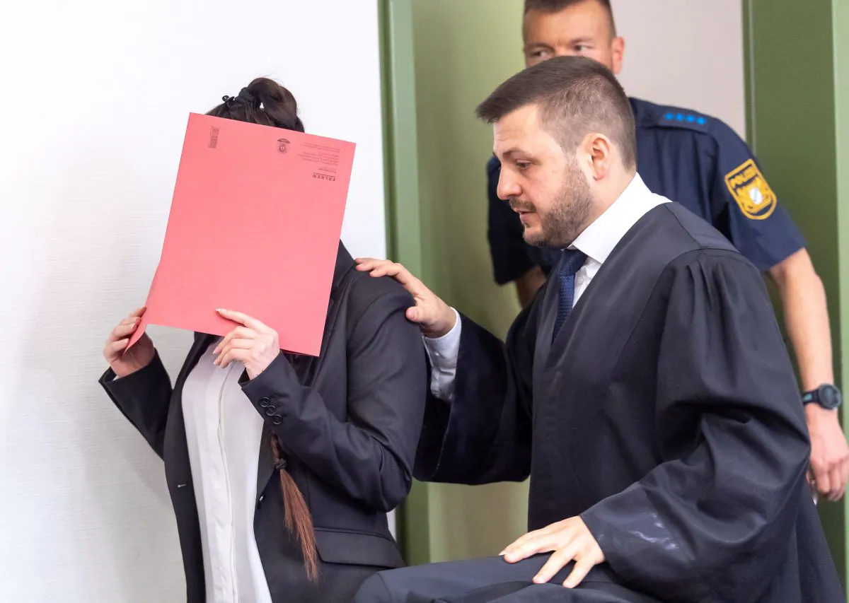 Defendant Jennifer W. (L) hides her face behind a folder and walks next to her lawyer Ali Aydin (R) as she arrives at court for the opening of her trial on April 9, 2019 in Munich, southern Germany. (Peter Kneffel/AFP/Getty Images)