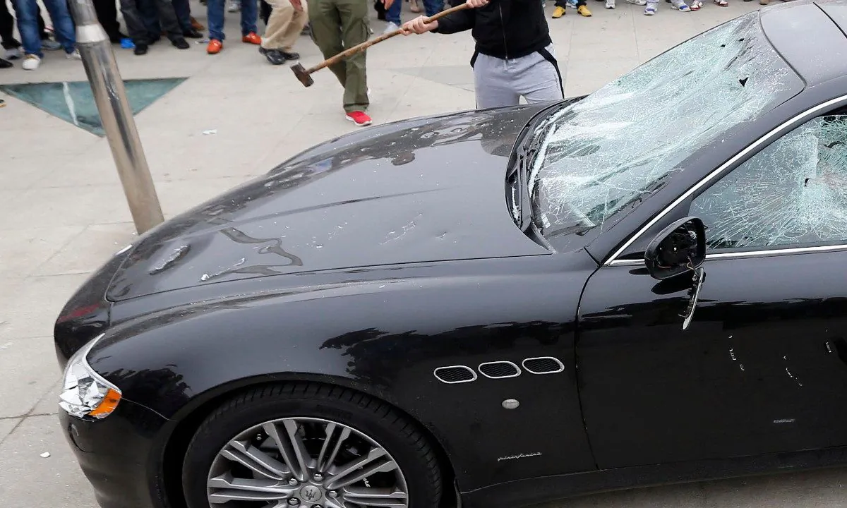 A rich business owner's Maserati being attacked by sledge hammers. (STR/AFP/Getty Images)