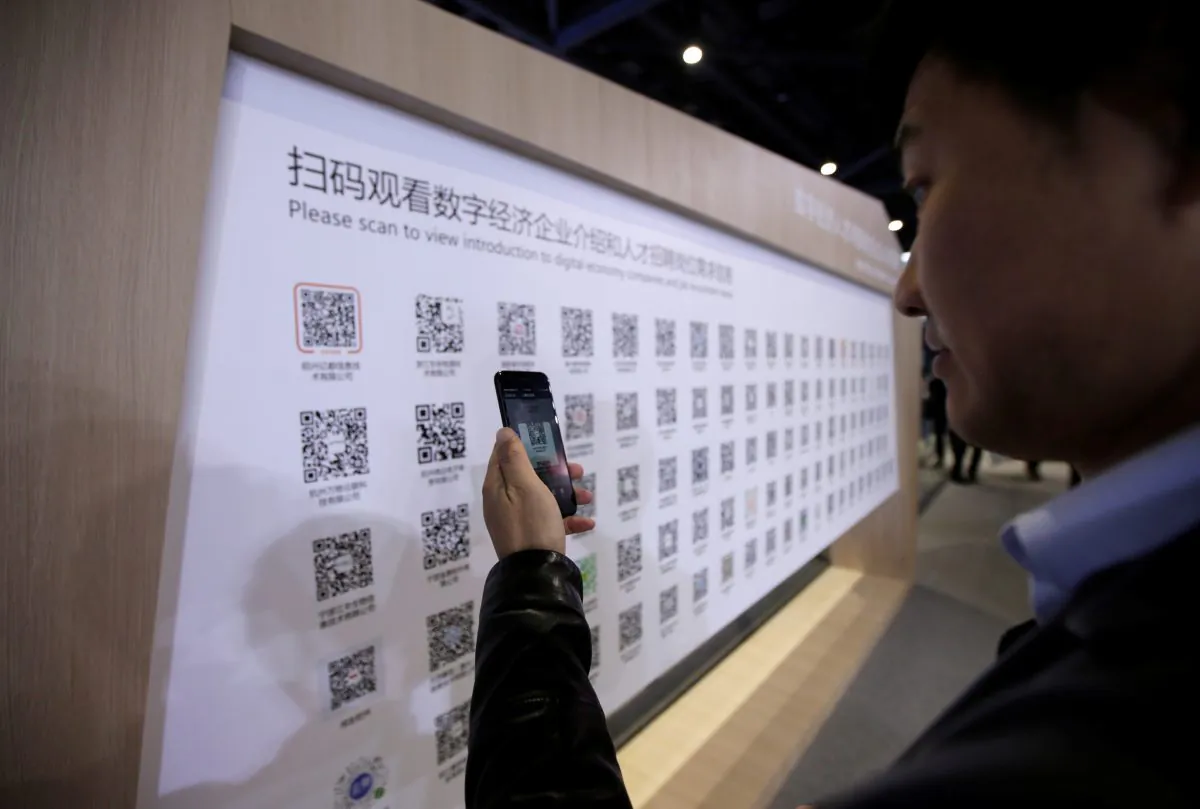 A man uses a mobile phone to scan the QR codes for job-seeking information during an internet expo at the fifth World Internet Conference (WIC) in Wuzhen, Zhejiang Province, China on Nov. 7, 2018. (Jason Lee/Reuters)