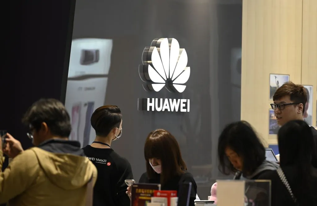 People stand next to a logo of Chinese telecoms giant Huawei at the Syntrend Creative Park in Taipei on Feb. 9, 2019. (Sam Yeh/AFP/Getty Images)