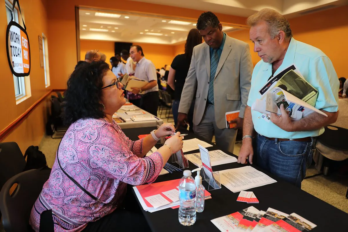 Betty Fernandez (L), from Macy's department store, speaks with Paul Cunningham about job openings during a job fair put on by Miami-Dade County and other sponsors in Miami, Fla., on April 05, 2019. (Joe Raedle/Getty Images)