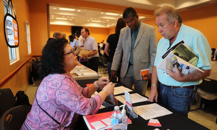 Betty Fernandez (L), from Macy's department store, speaks with Paul Cunningham about job openings during a job fair put on by Miami-Dade County and other sponsors in Miami, Fla., on April 05, 2019. (Joe Raedle/Getty Images)