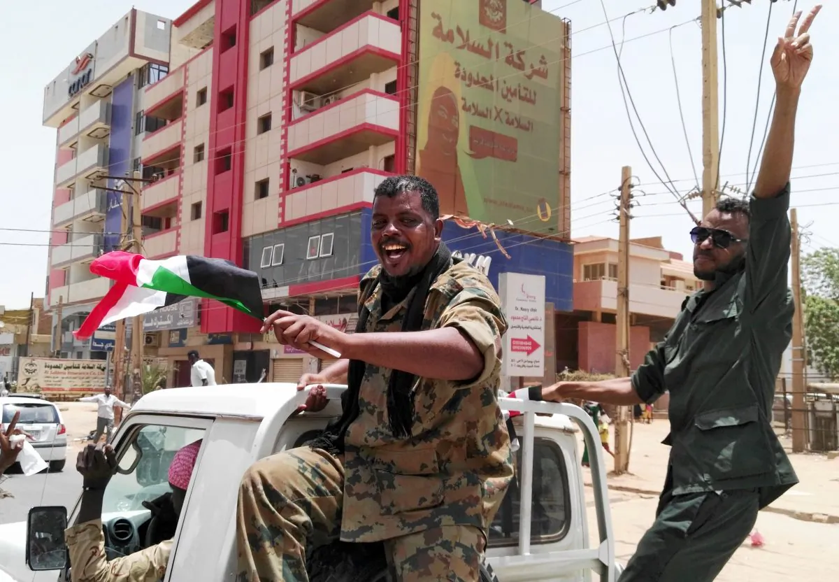 Members of the Sudanese security forces wave their national flag and flash the "V" for victory sign in the capital Khartoum on April 11, 2019. (-/AFP/Getty Images)