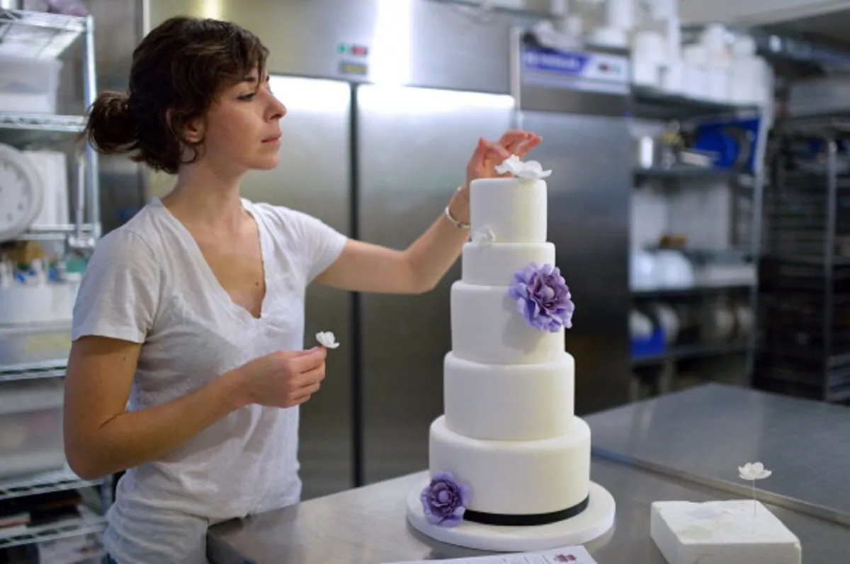 An employee of Sugarplum cake shop decorates a wedding cake for US residents in France in Paris, on October 26, 2012 .(Photo by ERIC FEFERBERG/AFP/Getty Images)