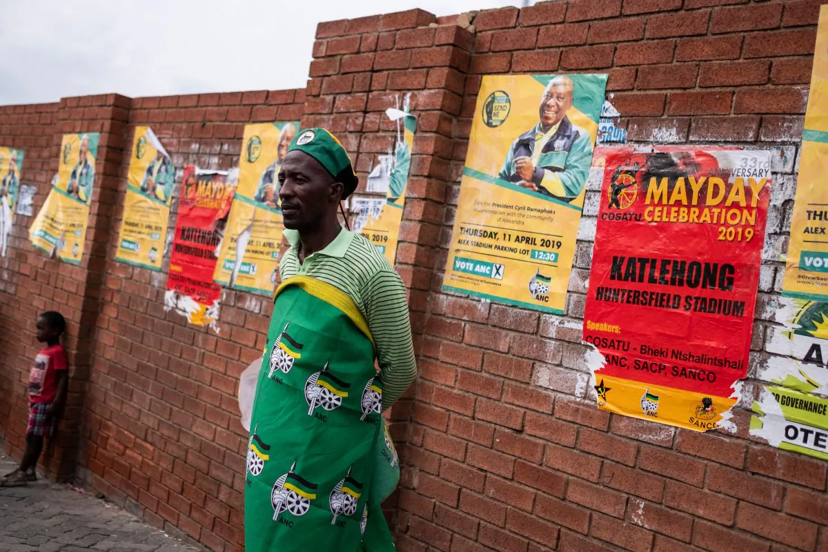 A man stands against a wall covered with election campaign ads on April 11, 2019, in Alexandra, South Africa. (Wikus de Wet/AFP/Getty Images)