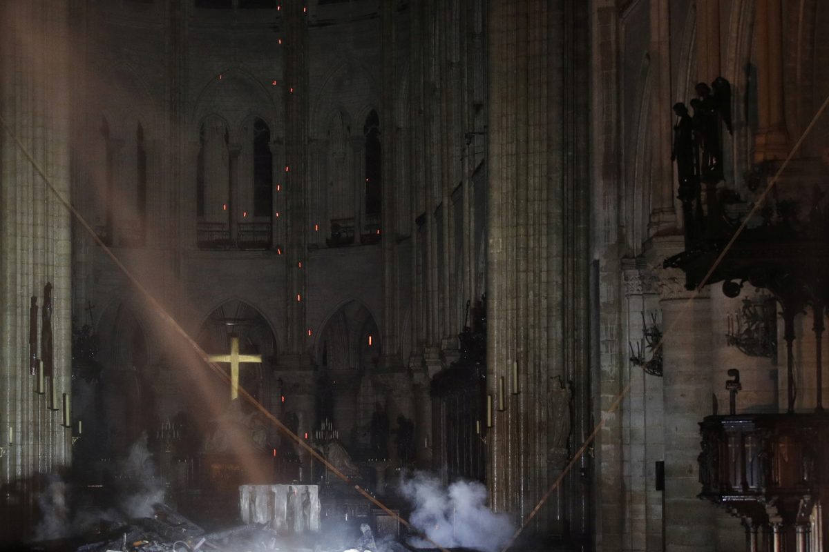 Smoke rises around the alter in front of the cross inside the Notre Dame Cathedral as a fire continues to burn in Paris
