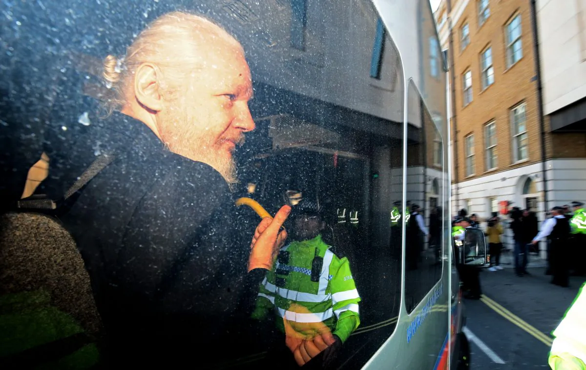 Julian Assange gestures to the media from a police vehicle on his arrival at Westminster Magistrates court in London, England, on April 11, 2019. (Jack Taylor/Getty Images)