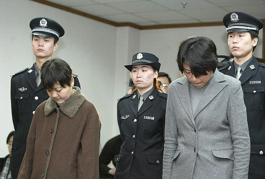 Police stand behind two defendants during a hearing at a Court in Beijing. (STR/AFP/Getty Images)