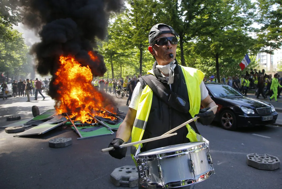 A man bangs a drum in front of a fire on the street during a yellow vest demonstration in Paris, on April 20, 2019. (Michel Euler/AP Photo)