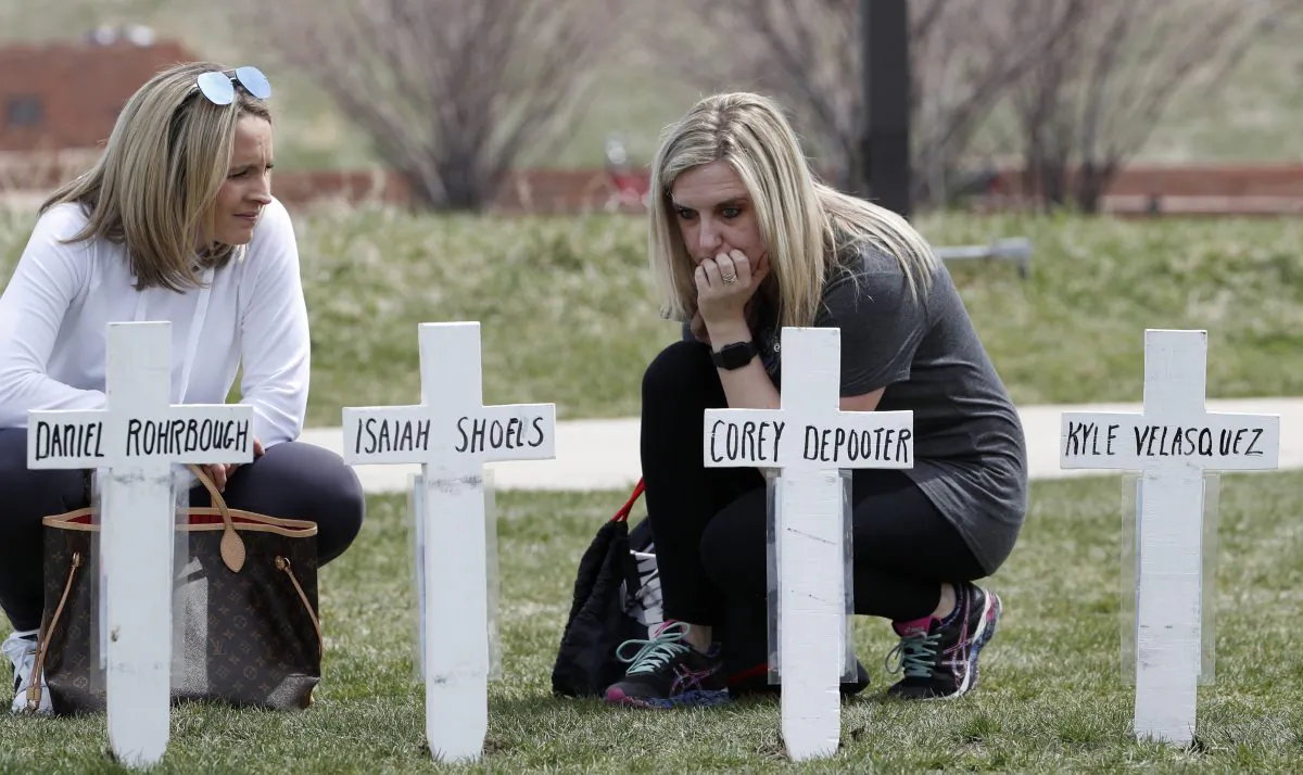 Cassandra Sandusky (R) a graduate of Columbine High School, pauses at a row of crosses bearing the names of the victims of the attack at the school 20 years ago before a remembrance for the victims in Littleton, Colo. on April 20, 2019. (David Zalubowski/AP Photo)