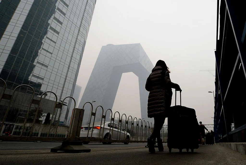A woman walks past the CCTV tower in Beijing on Dec. 8, 2015. (STR/AFP/Getty Images)