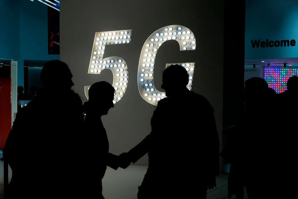 Visitors shake hands next to a 5G hotspot sign at the Mobile World Congress (MWC) in Barcelona on Feb. 27, 2019. (Pau Barrena/AFP/Getty Images)