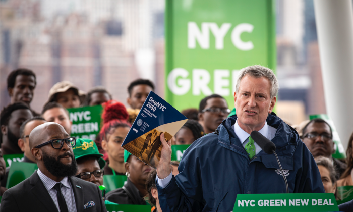 New York City Mayor Bill de Blasio holds up a copy of 'One NYC 2050' as he speaks about the city's response to climate change at Hunters Point South Park in the Queens borough of New York City on April 22, 2019. (Drew Angerer/Getty Images)