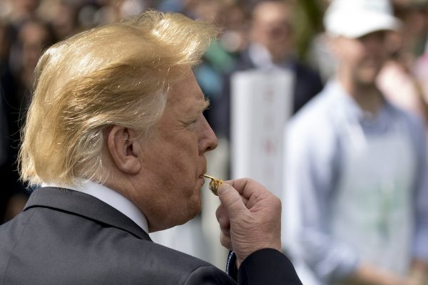 President Donald Trump blows the whistle to start a race