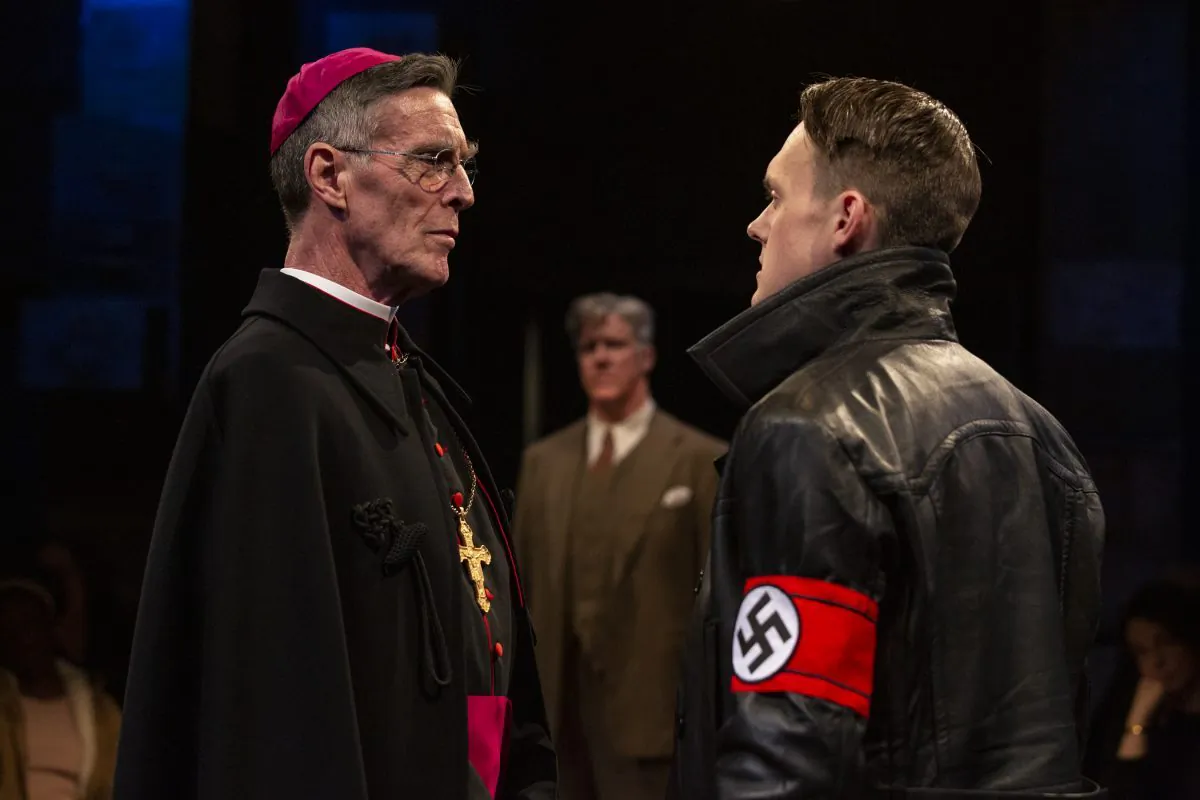 A difference of opinion: Bishop von Galen (John Glover, L) opposes the National Socialist German Workers Party policies enforced by the deputy director of a clinic for disabled children (Sam Lilja), while the clinic’s doctor, Dr. Victor Franz (Karl Kenzler) looks on. (Maria Baranova)