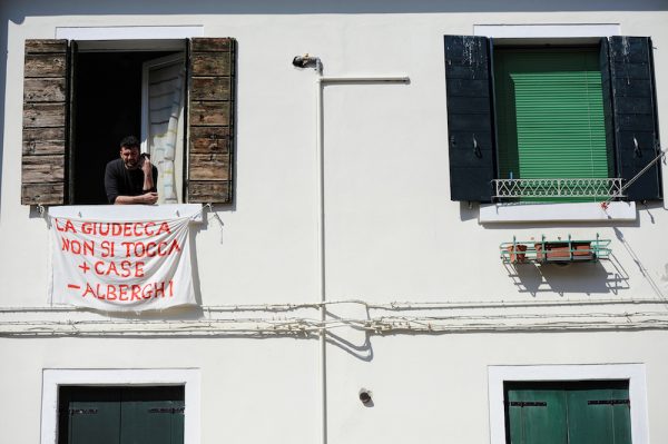 Alessandro Dus, 34, talks on the phone in his illegally occupied apartment in the Casette neighbourhood in Venice