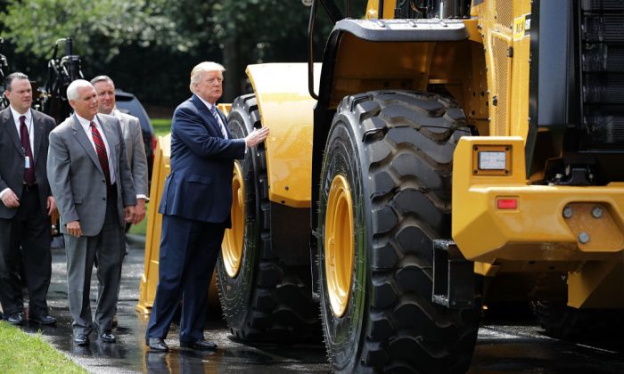 U.S. President Donald Trump touches a wheel loader made by Caterpillar while touring a Made in America product showcase with Vice-President Mike Pence on the South Lawn of the White House in Washington on July 17, 2017 (Chip Somodevilla/Getty Images)