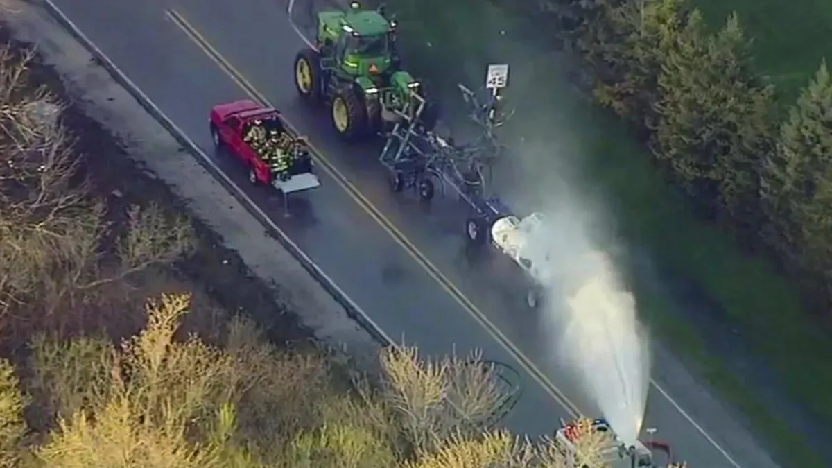 In this still image from video provided by ABC7 Chicago, a fire engine sprays water on a container of the chemical that farmers use for soil after after anhydrous ammonia leaked in Beach Park, Ill., on April 25, 2019. (ABC7 Chicago via AP)