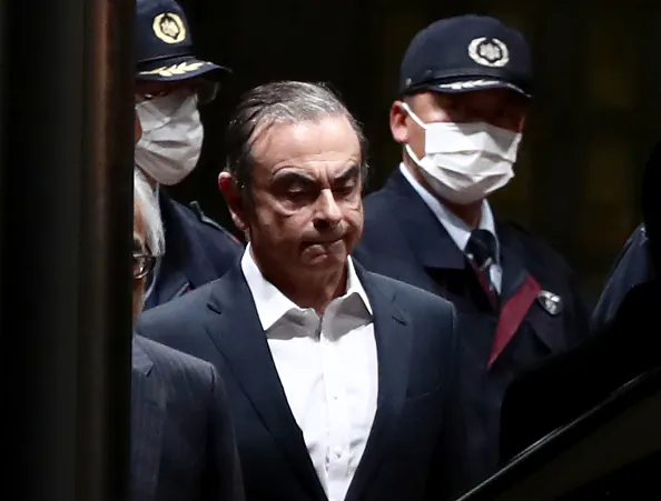 Former Nissan Chairman Carlos Ghosn (C) is escorted as he walks out of the Tokyo Detention House following his release on bail in Tokyo on April 25, 2019. BEHROUZ MEHRI/AFP/Getty Images
