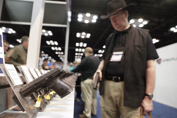 A gun enthusiast looks over the display of Beretta pistols on display in the exhibition hall