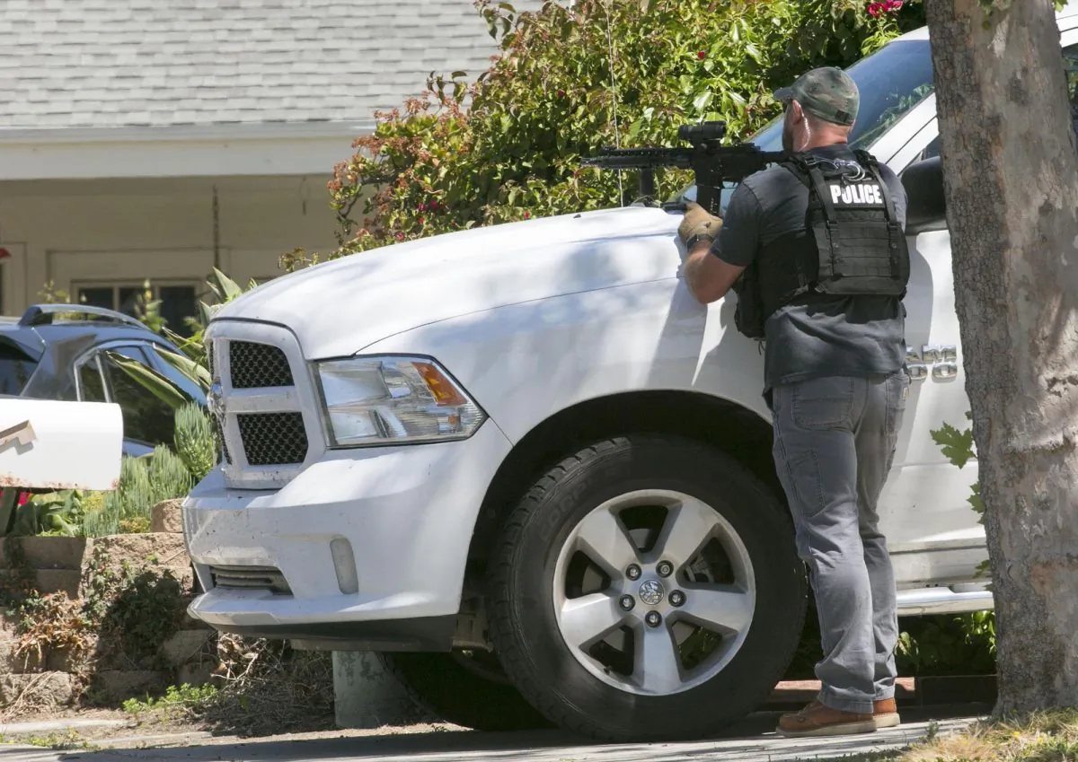 In this file photo, a San Diego Police officer keeps aim on a house in San Diego, Calif., on April 27, 2019. (John Gibbins/The San Diego Union-Tribune via AP)