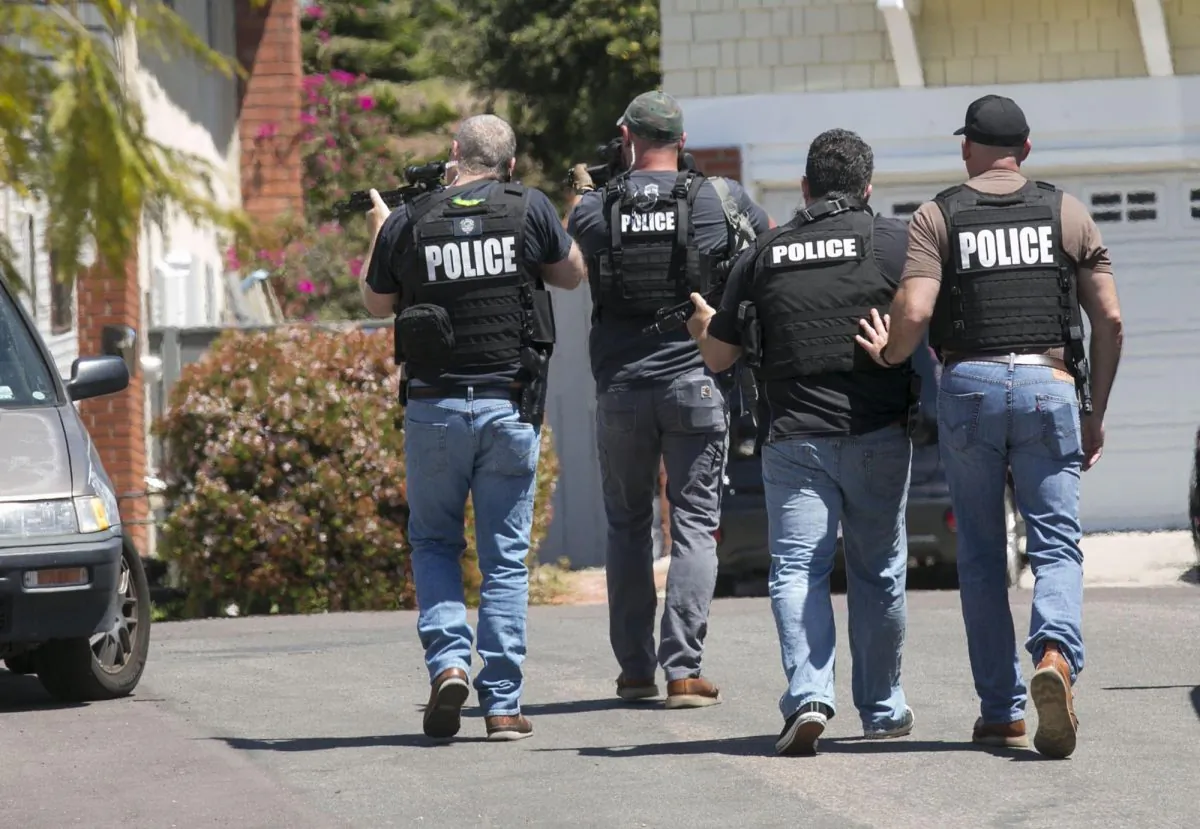 Heavily armed San Diego police officers approach a house in this file photo taken in San Diego, Calif., on April 27, 2019. (John Gibbins/The San Diego Union-Tribune via AP)