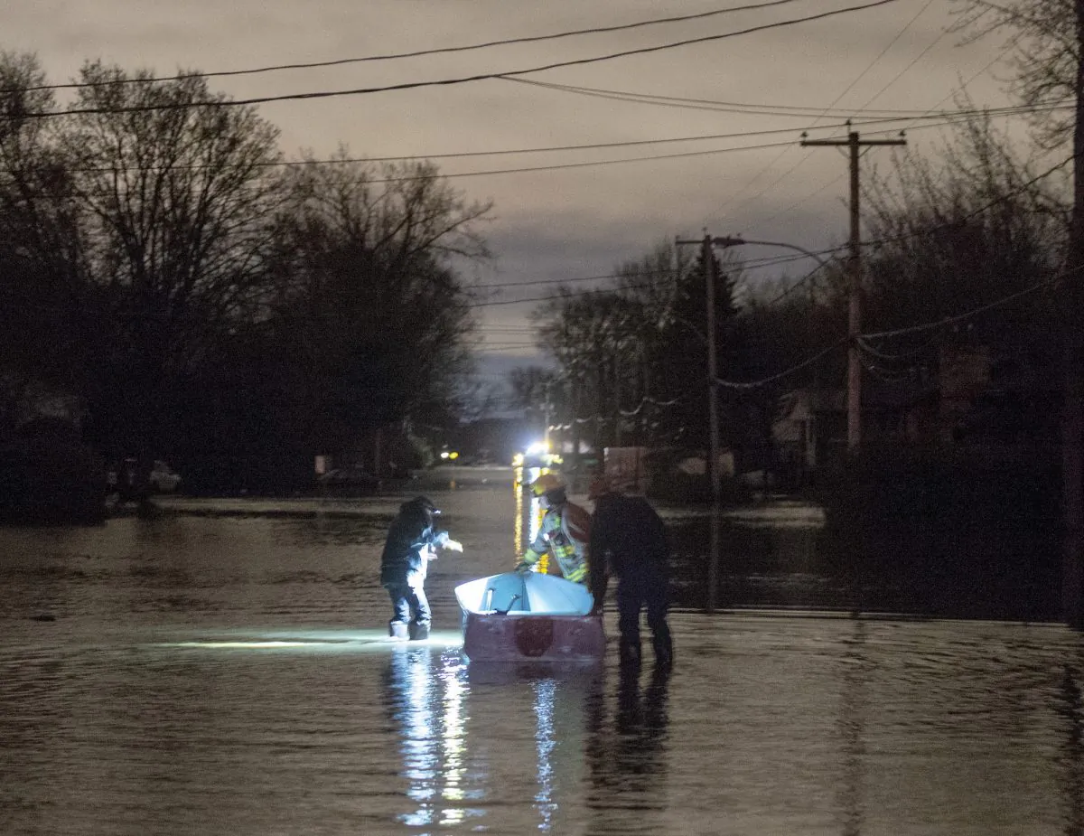 Residents use a boat to make their way through flood waters after a dike broke causing widespread flooding and focing hundreds of people to evacuate in Ste-Marthe-sur-le-Lac, Que., on April 27, 2019. (The Canadian Press/Ryan Remiorz)