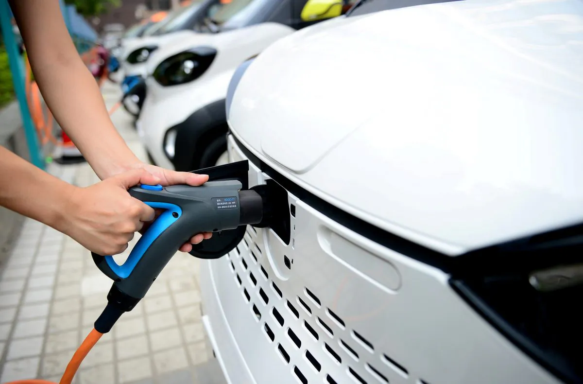 A staff member hooks up a charging cable to an electric vehicle (EV) at a charging station in Liuzhou, Guangxi Zhuang Autonomous Region, China on July 31, 2017. (Reuters)