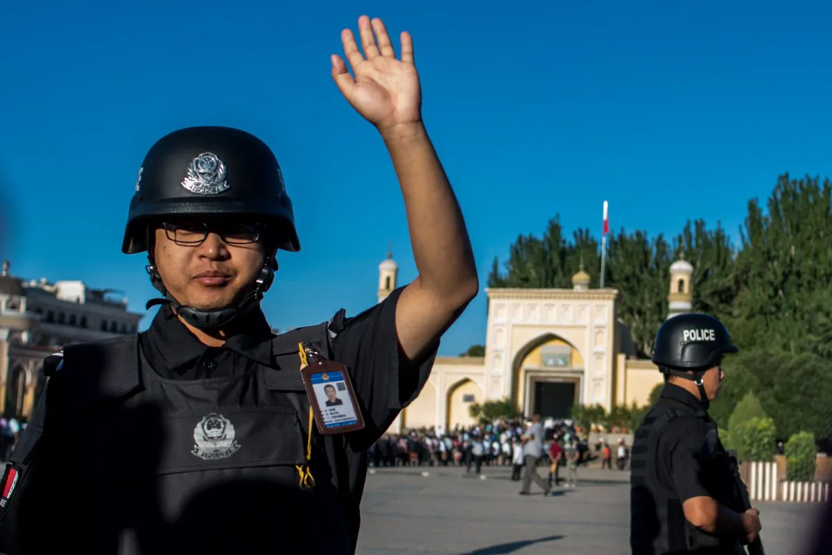 This picture taken on June 26, 2017 shows a policeman gesturing as Muslims arrive at the Id Kah Mosque for the morning prayer on Eid al-Fitr in the old town of Kashgar in China's Xinjiang Uighur Autonomous Region. (Johannes Eisele/AFP/Getty Images)