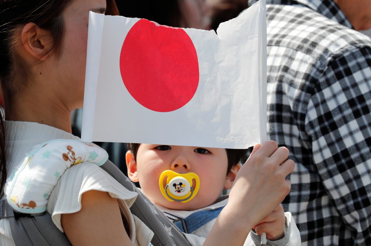 A baby holds a Japanese national flag