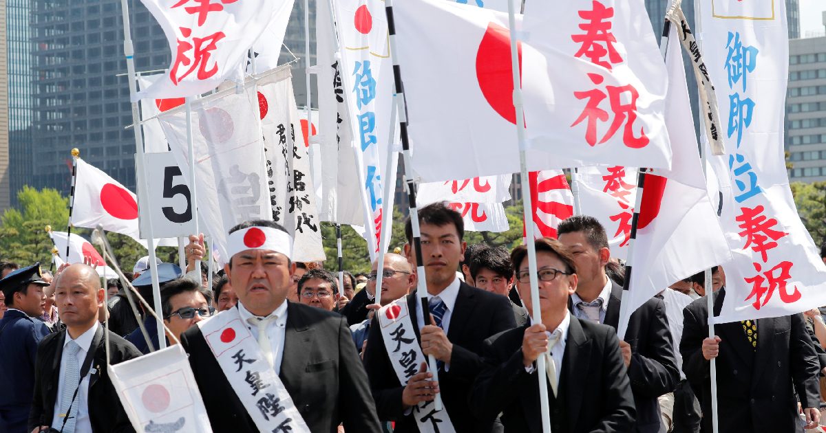 Well-wishers with flags wait in line to enter the Imperial Palace