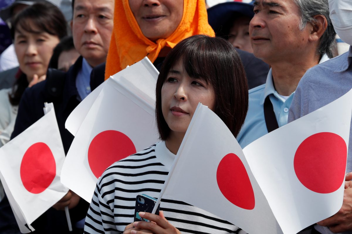 A woman holds a flag as she waits in line outside the Imperial Palace