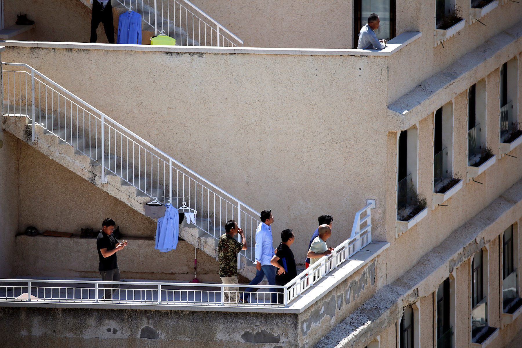 Chinese workers look on as an Iron Dome anti-missile projectile intercepts a rocket that was fired from Gaza, above the Israeli city of Ashkelon