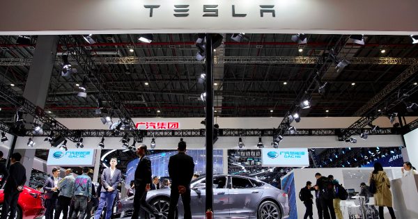 People visit a Tesla booth during the media day