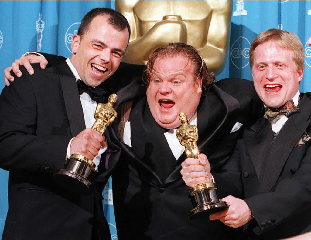 Comedian-actor Chris Farley (C) poses with filmmakers Tyron Montgomery (L) and Thomas Stellmach (R) after they won an Oscar for best animated short film for "Quest" during the 69th Annual Academy Awards in Los Angeles, Cali., on March 24, 1997. (Vince Bucci/AFP/Getty Images)